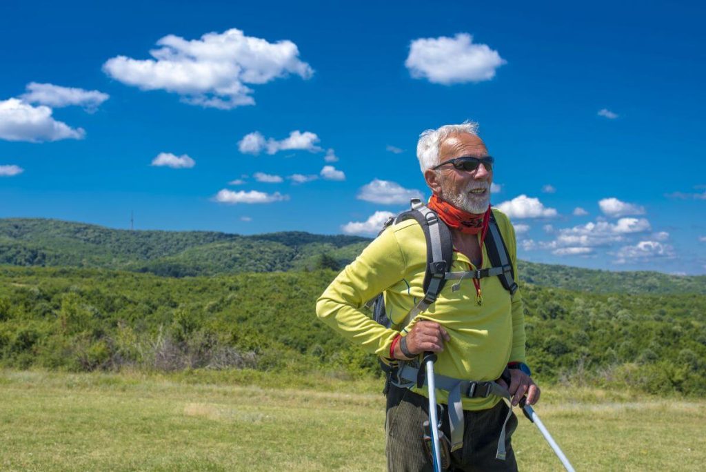 Active senior hiking in Swiss Alps with walking poles – safe adventures for seniors