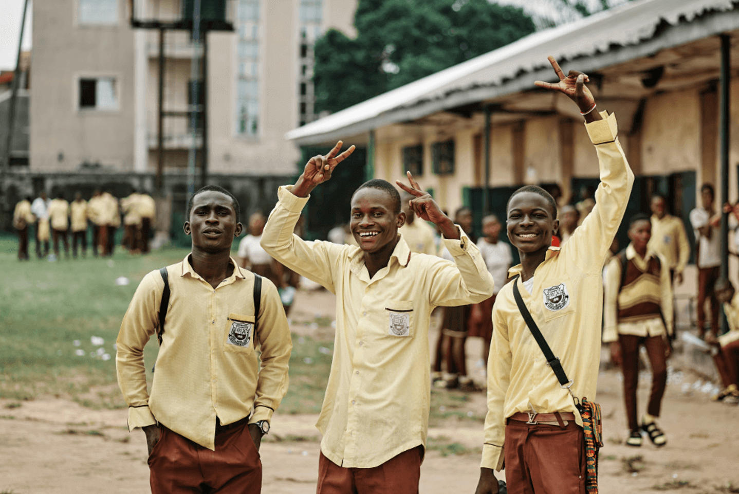 Stereotypes about Africa: Smiling African students in school uniforms making peace signs — daily life in Accra or Lagos
