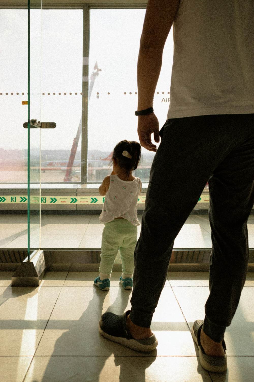 Father and daughter looking out the airport window while waiting to board a flight