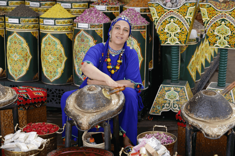 Free things to do in Marrakech: Local vendor in blue traditional dress selling spices at a vibrant market stall in the Medina