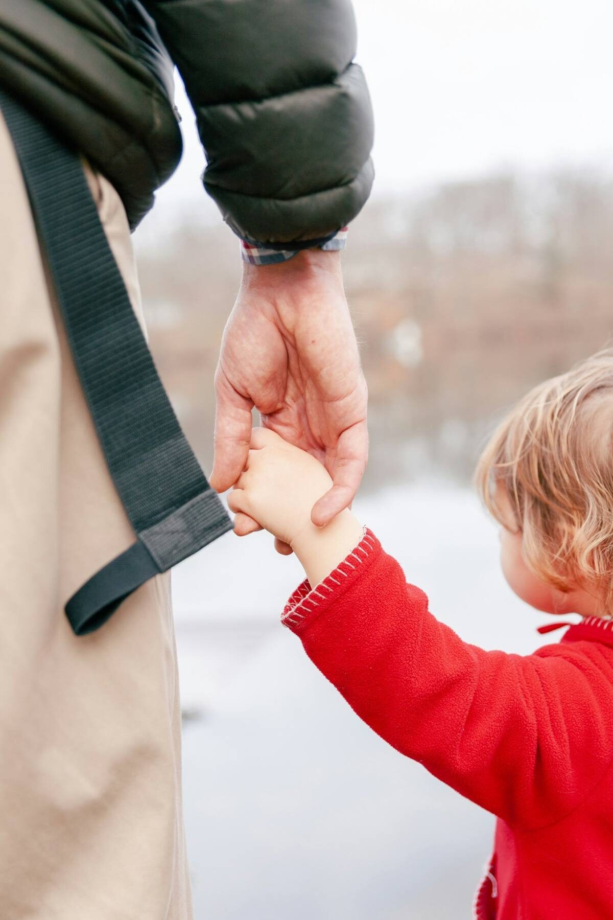 Parent holding a child's hand while traveling together