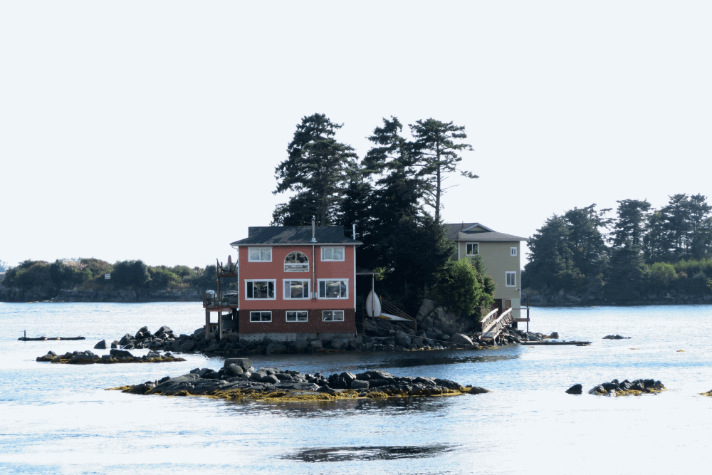 Eco-lodging in Sitka, Alaska — a pink house on a rocky island, surrounded by water and evergreens. Sustainable travel that respects marine ecosystems