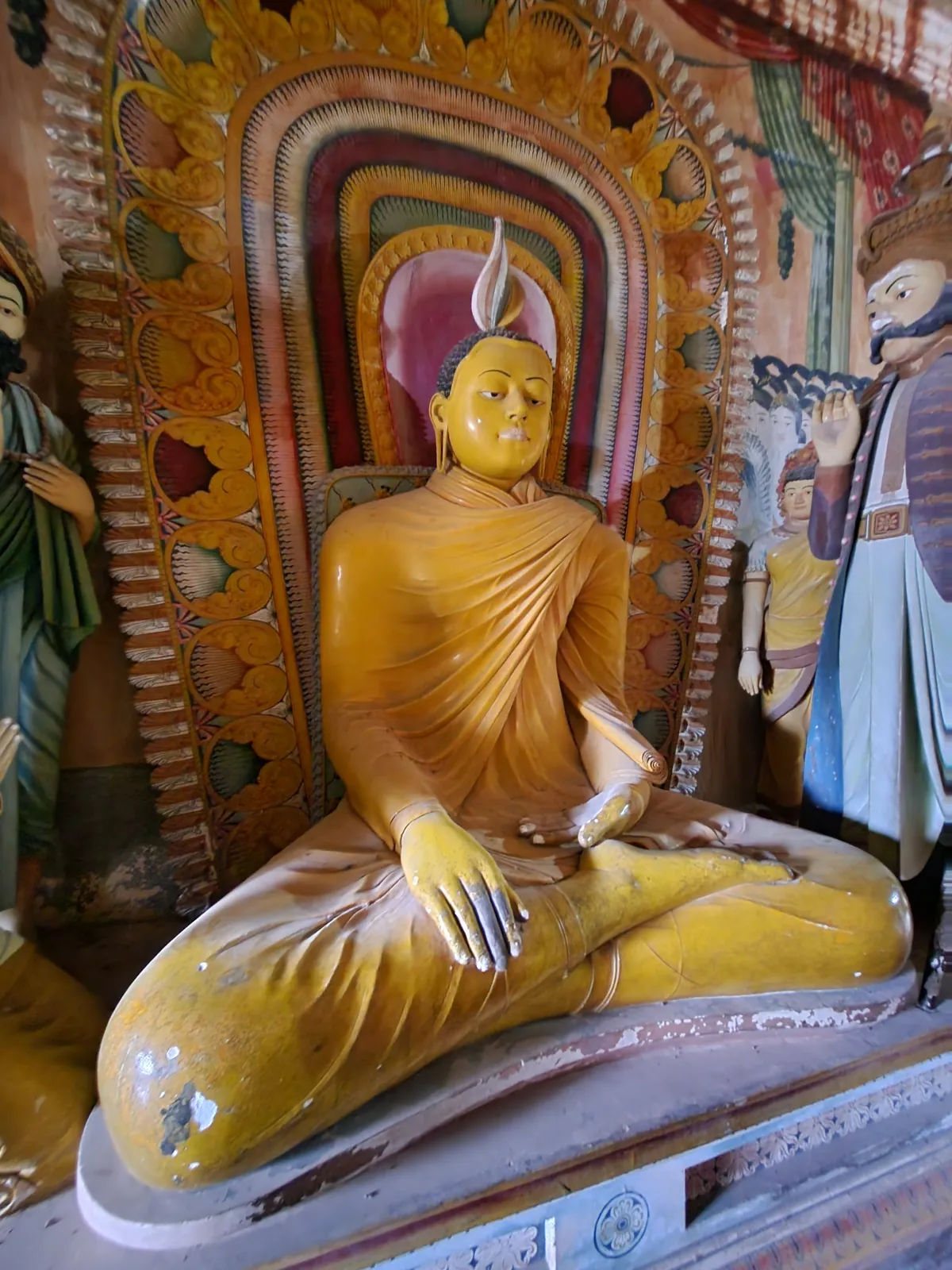 Golden Buddha statue framed by an ornate makara torana arch at Buddhist temples in Sri Lanka